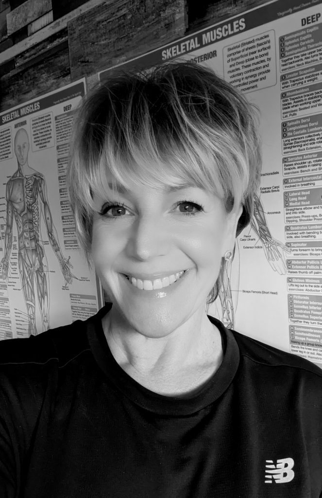 picture of Claire standing in front of a diagram of the muscles of the body